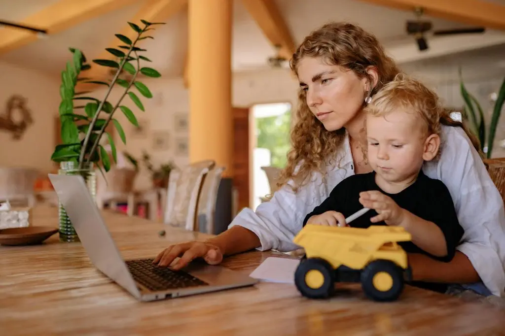 a woman using a laptop with her son
